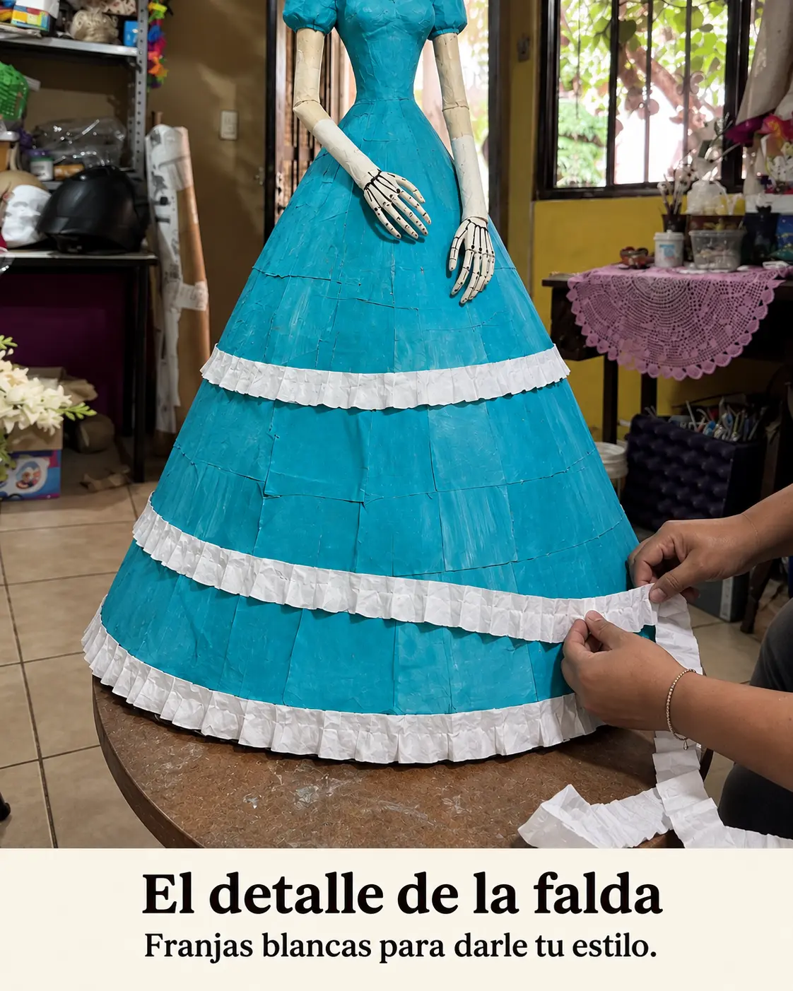 Manos añadiendo la última franja blanca a la falda turquesa
